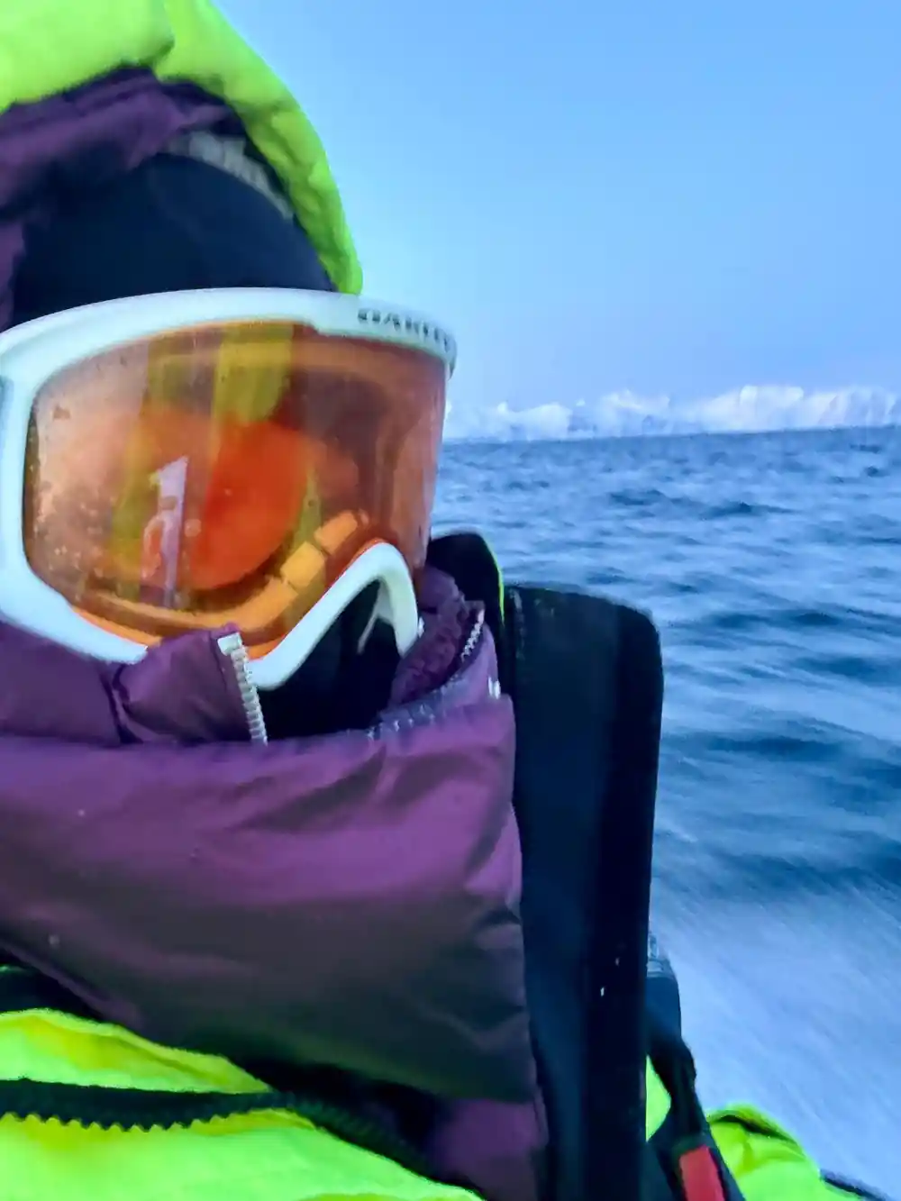 A passenger in ski goggles and a thermal hood aboard the boat